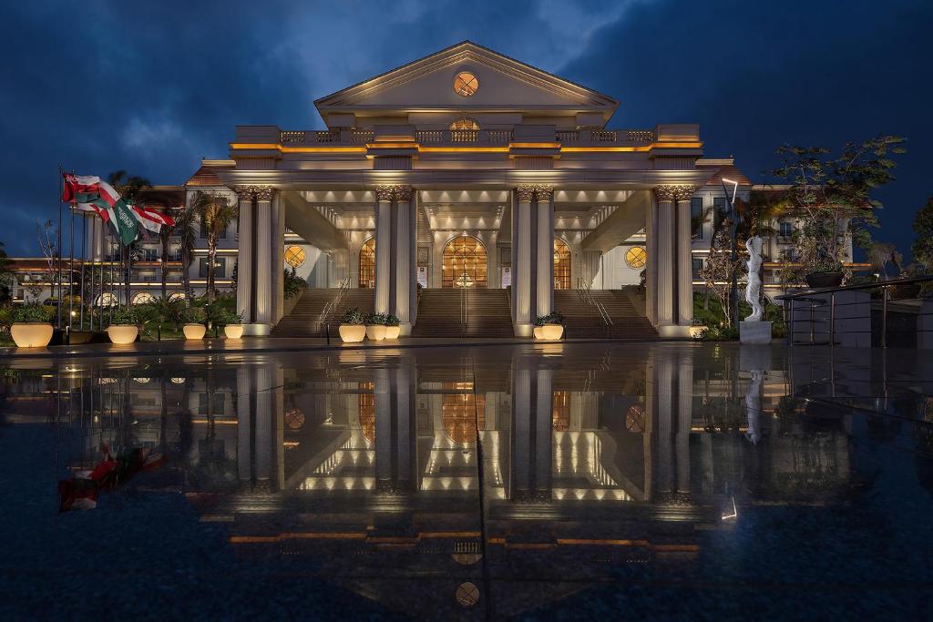 un edificio con un reflejo en el agua por la noche en The St Regis New Capital Cairo en El Cairo