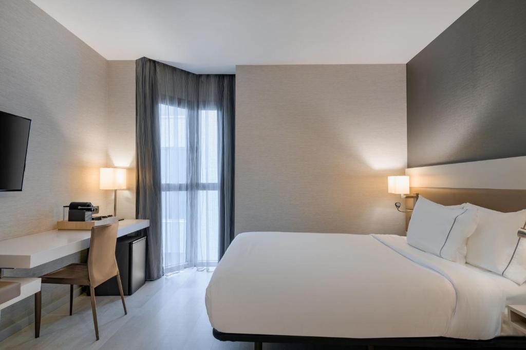 um quarto de hotel com uma cama, uma secretária e uma janela em SH Colón Valencia em Valência