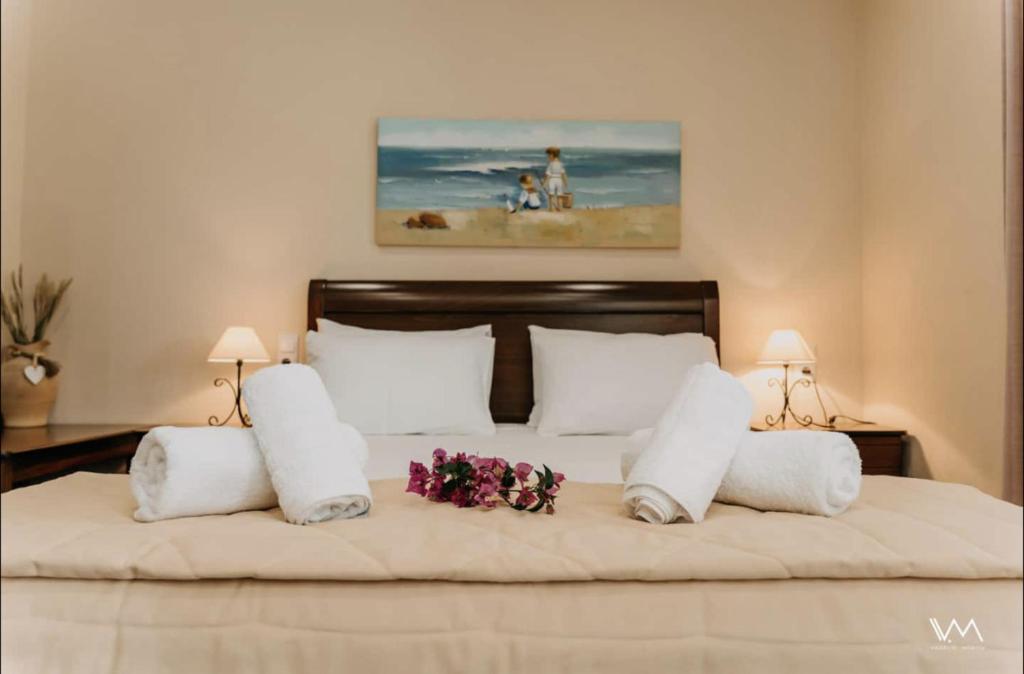 a large bed with white pillows and flowers on it at Amalthea Sivota in Sivota