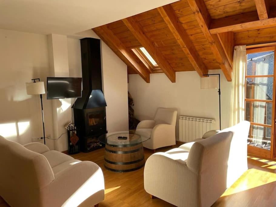 sala de estar con 2 sillas, mesa y chimenea en Apartamento familiar en Benasque en Eriste