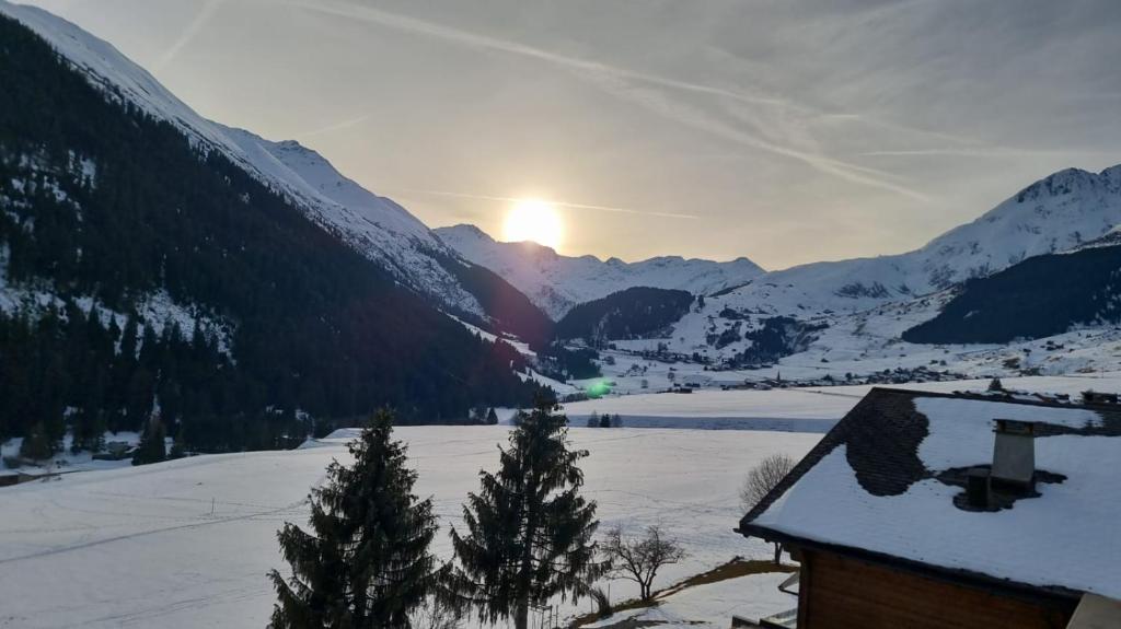 a view of a snow covered valley with the sun setting at Apartment Margherita in Sedrun