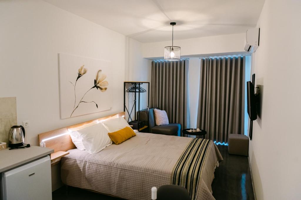 um quarto com uma cama, uma cadeira e uma janela em MAGNOLIA SUITES em Lepanto