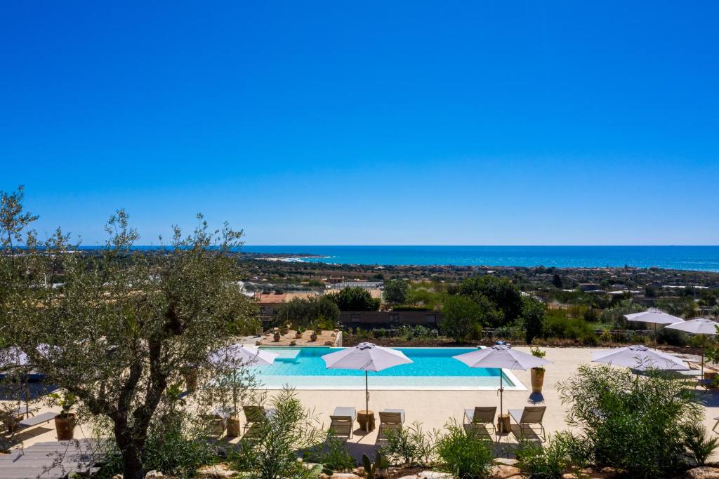 - une vue sur la piscine avec parasols et l'océan dans l'établissement RoccaSeta, à Scicli