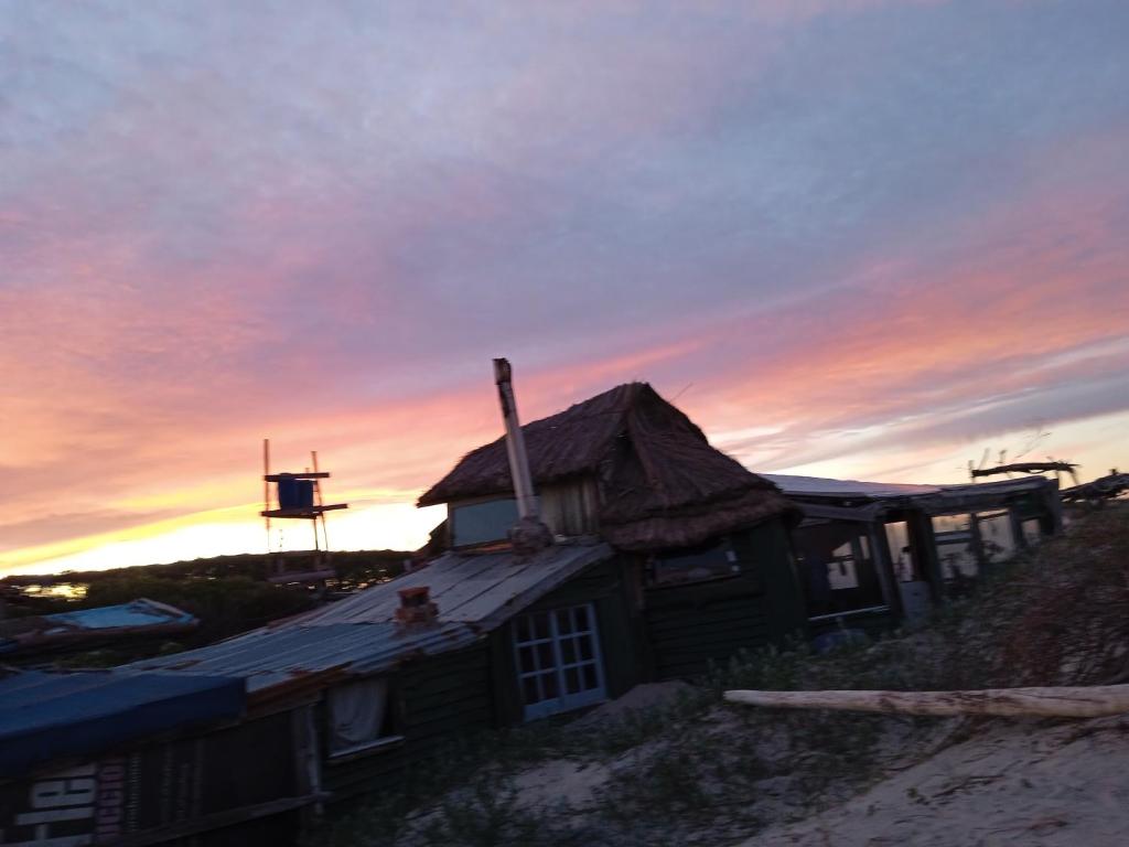una casa en la playa con una puesta de sol en el fondo en Para un poquito relax en Barra de Valizas