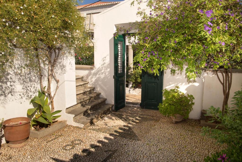 una porta verde in un edificio bianco con alberi di 1861 Mansion Spetses a Spetses