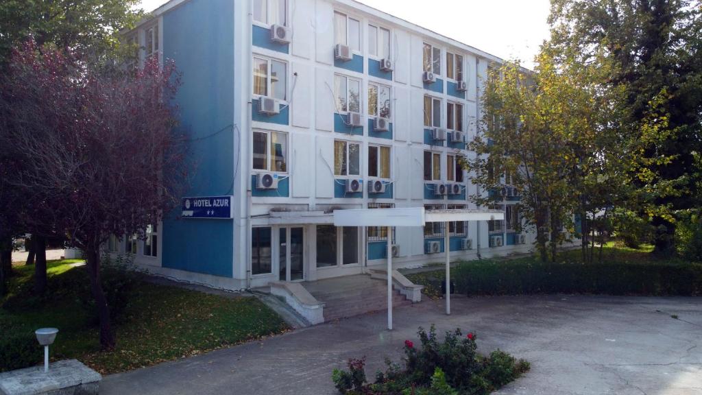 een groot blauw-wit gebouw met een parkeerplaats bij Hotel Azur in Eforie Nord