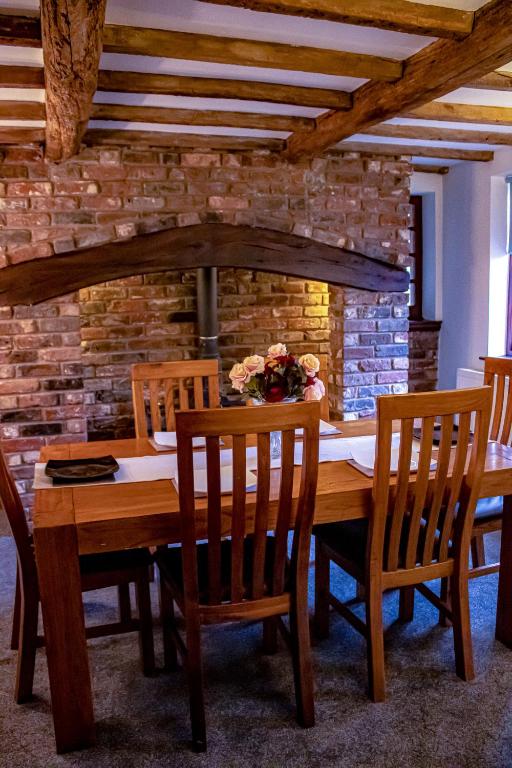 a dining room table with chairs and a brick wall at Forget Me Not Cottage in Ironbridge