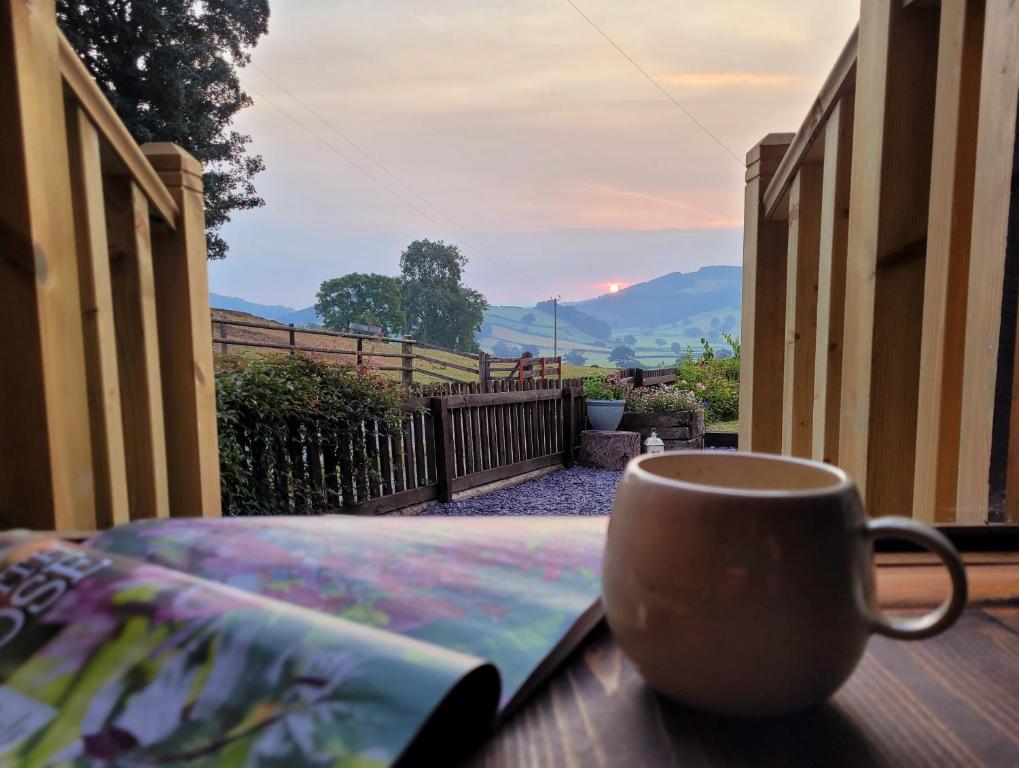 a coffee cup sitting on a table with a book at Kettle Tree Cabin in Welshpool