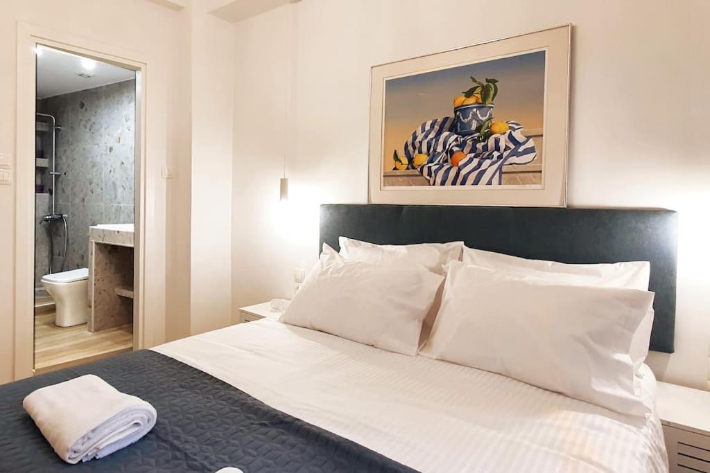 Schlafzimmer mit einem Bett mit weißer Bettwäsche und einem Spiegel in der Unterkunft Acropolis Thisio Apartment 2 bedrooms 2 bathrooms in Athen
