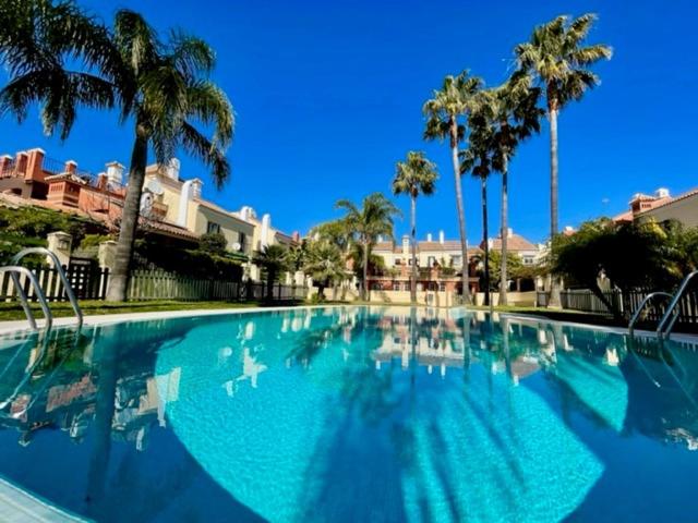 una gran piscina azul con palmeras en GATU PREMIUM Villa Mar de Arabia, en El Puerto de Santa María