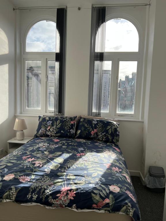 een slaapkamer met een bed met een bloemenbed en 2 ramen bij 2 bedroom city centre apartment 35 Victoria street in Liverpool