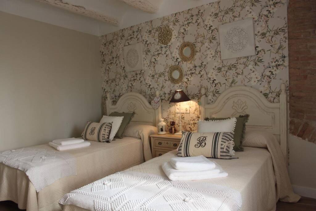 two twin beds in a room with floral wallpaper at El Géiser de Pozuelo in Pozuelo de Aragón