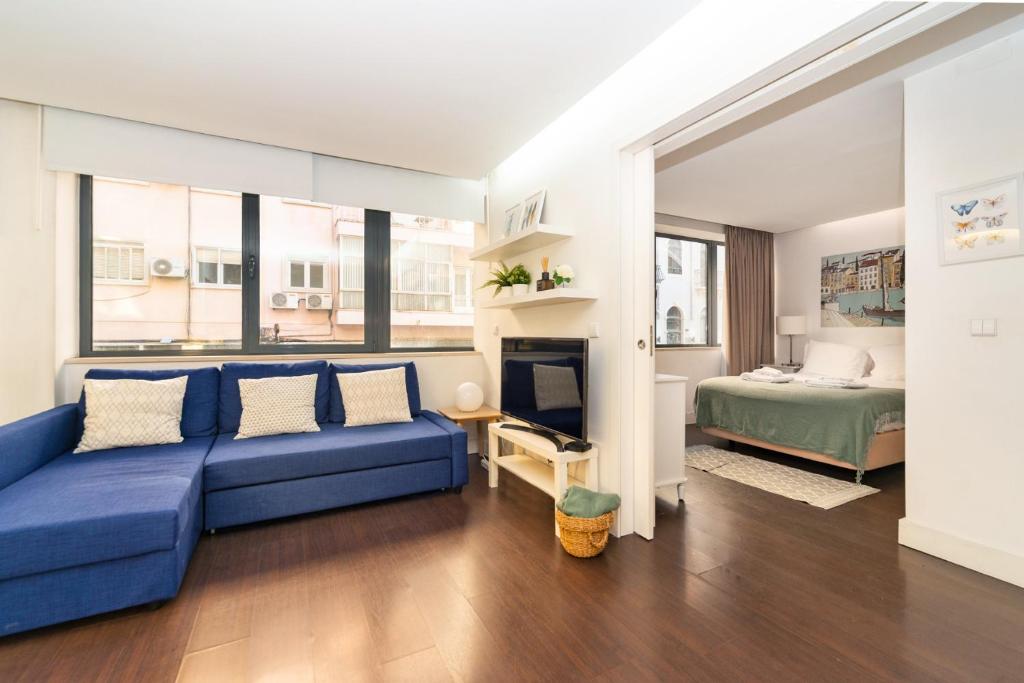 un soggiorno con divano blu e letto di Comfortable Apartment in Marquês de Pombal a Lisbona