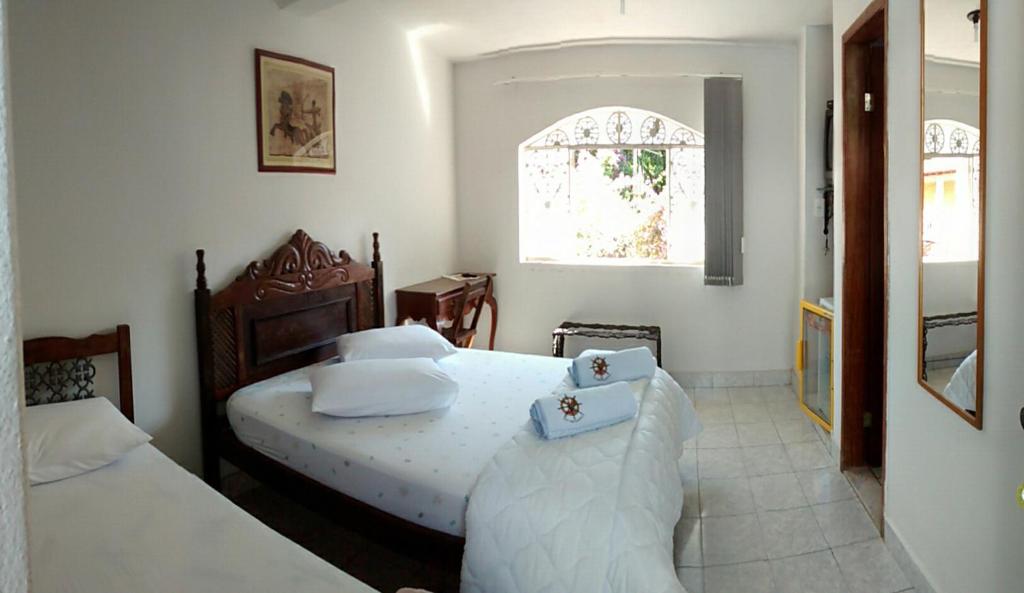 1 dormitorio con 2 camas y ventana en Pousada do Mendonça, en Juiz de Fora
