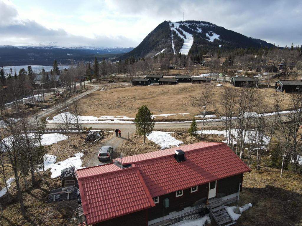 una casa con techo rojo frente a una montaña en Stuga , Funäsdalen, en Funäsdalen