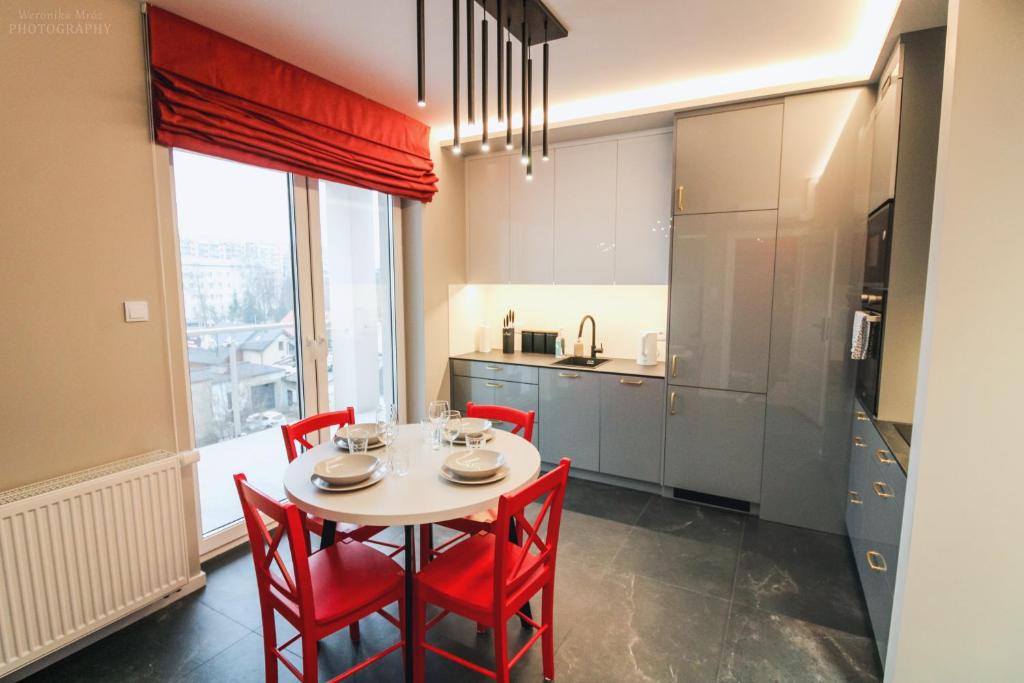 une cuisine avec une table blanche et des chaises rouges dans l'établissement D Apartments Centrum Ogień, à Białystok
