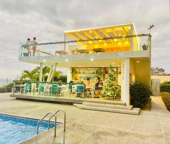 a house with a pool and people standing on the balcony at Vacaciones Playa Azul in Tonsupa