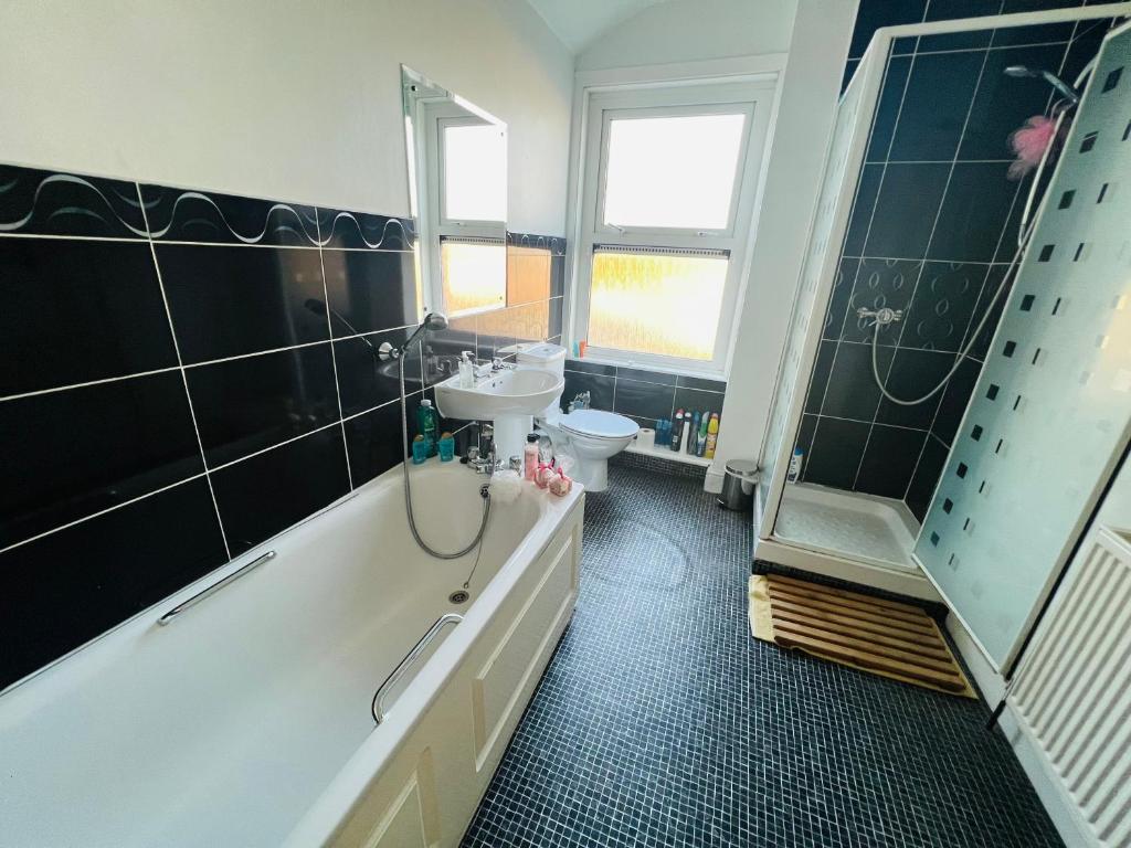 a bathroom with a tub and a sink and a toilet at Cozy One bedroom house with garden in Luton in Luton