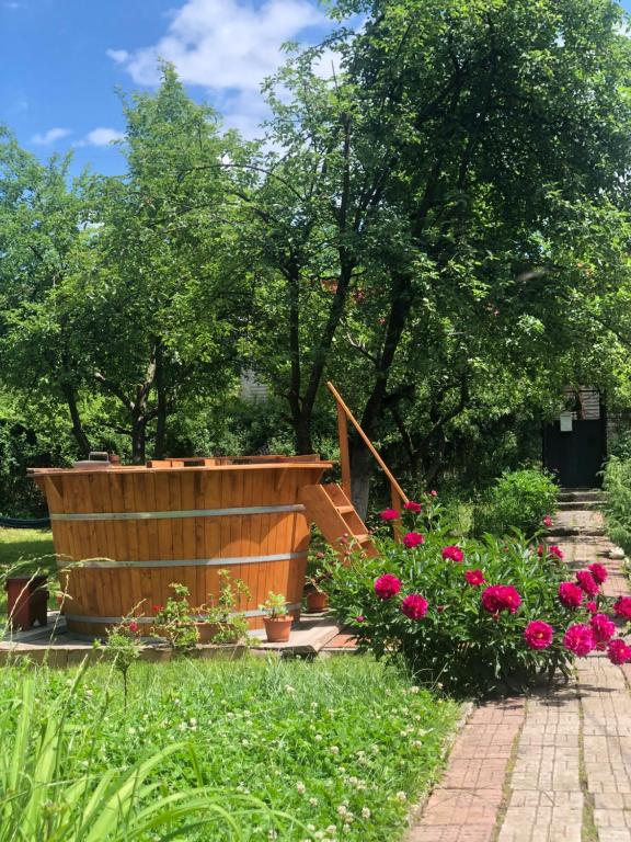 een houten hot tub in een tuin met roze bloemen bij Casa la Raisa in Lupeni