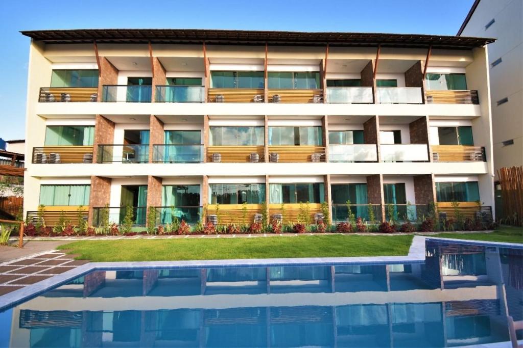 an apartment building with a swimming pool in front of it at Condomínio Velas do Porto in Porto De Galinhas