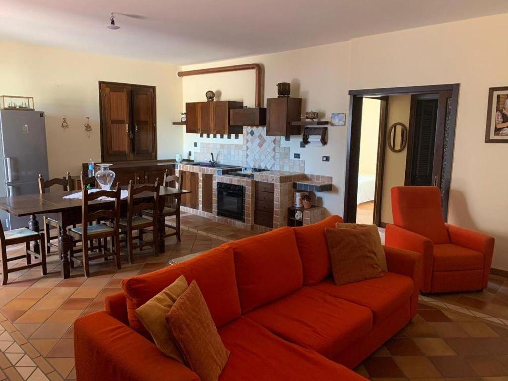 ein Wohnzimmer mit einem orangenen Sofa und einer Küche in der Unterkunft Villetta Girasole in Gallipoli