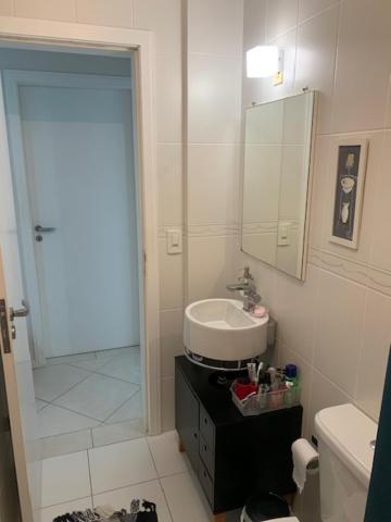 y baño con lavabo, aseo y espejo. en Apartamento aconchegante próximo ao mar, en Florianópolis