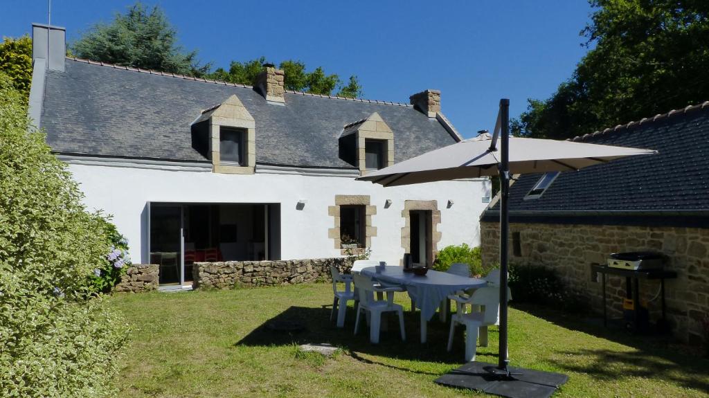 a white house with a table and an umbrella at Belle longère en campagne à Larmor Baden in Larmor-Baden