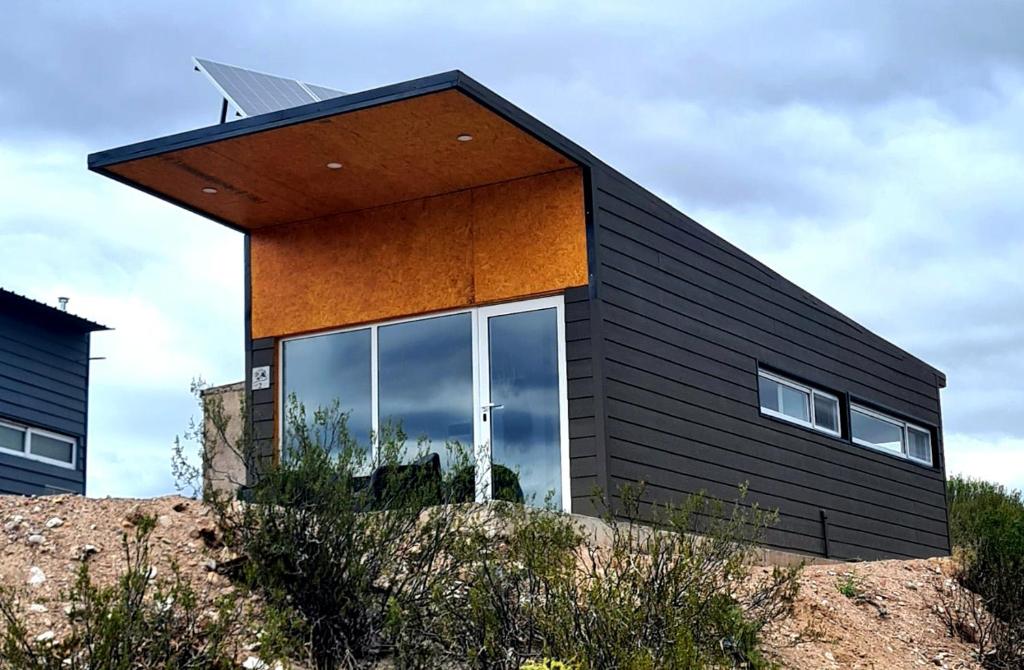 een zwart huis bovenop een zandheuvel bij Piuquenes 2 in Potrerillos