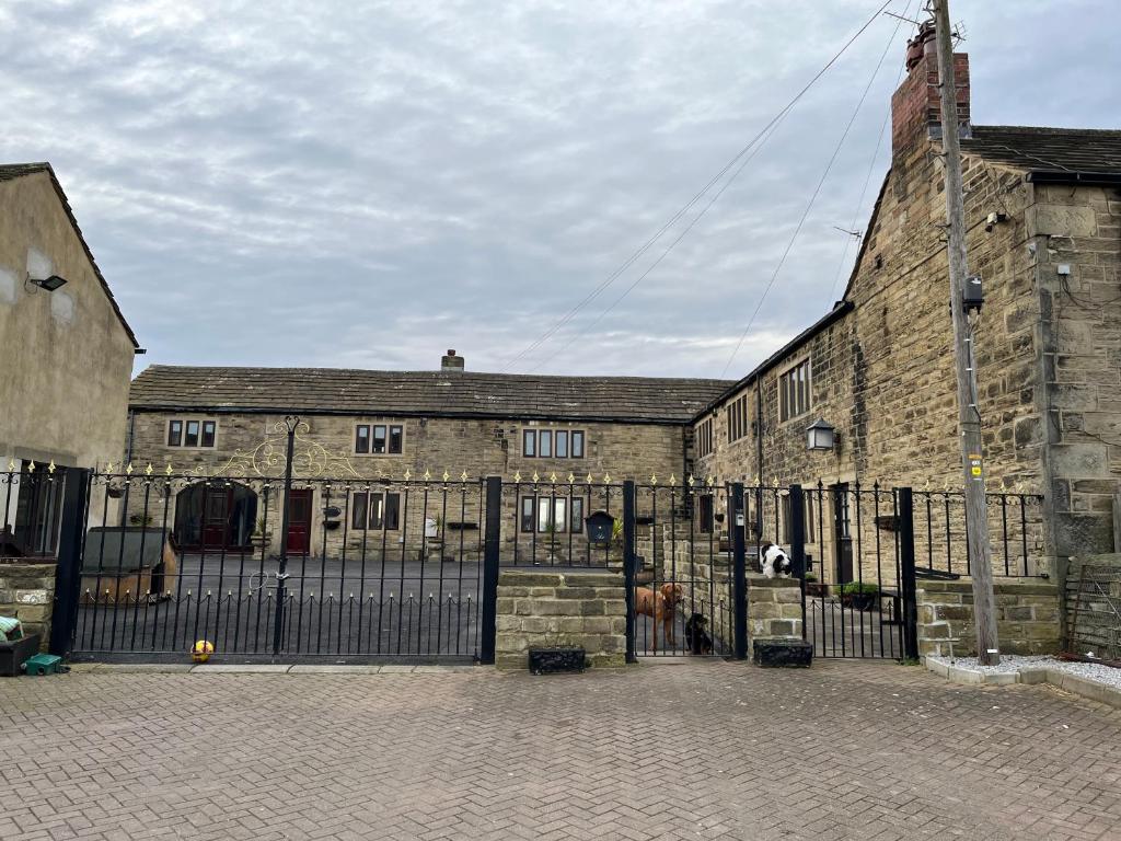 an old stone building with a gate in front of it at The Farm House Modern spacious 2 bedroom home at Tong road Leeds perfect for contractors free secure parking in Stanningley