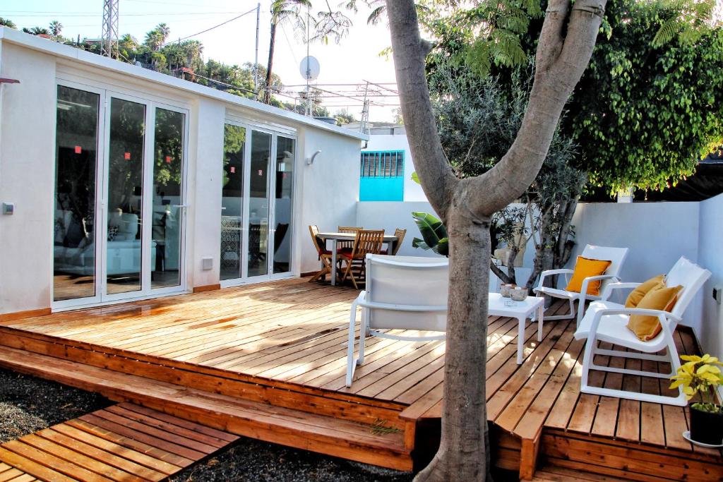 a wooden deck with white chairs and a tree at FINCA BEROLO 1 in Guía de Isora