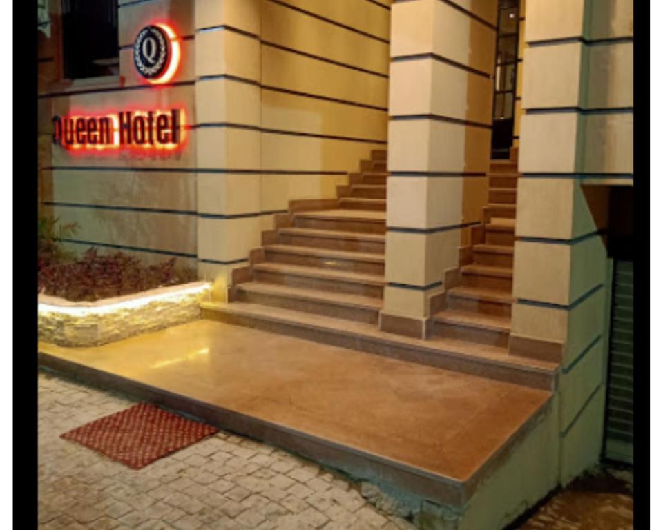 eine Treppe außerhalb eines Gebäudes mit Neonschild in der Unterkunft Queen Hotel Fayoum in Al-Fayyūm