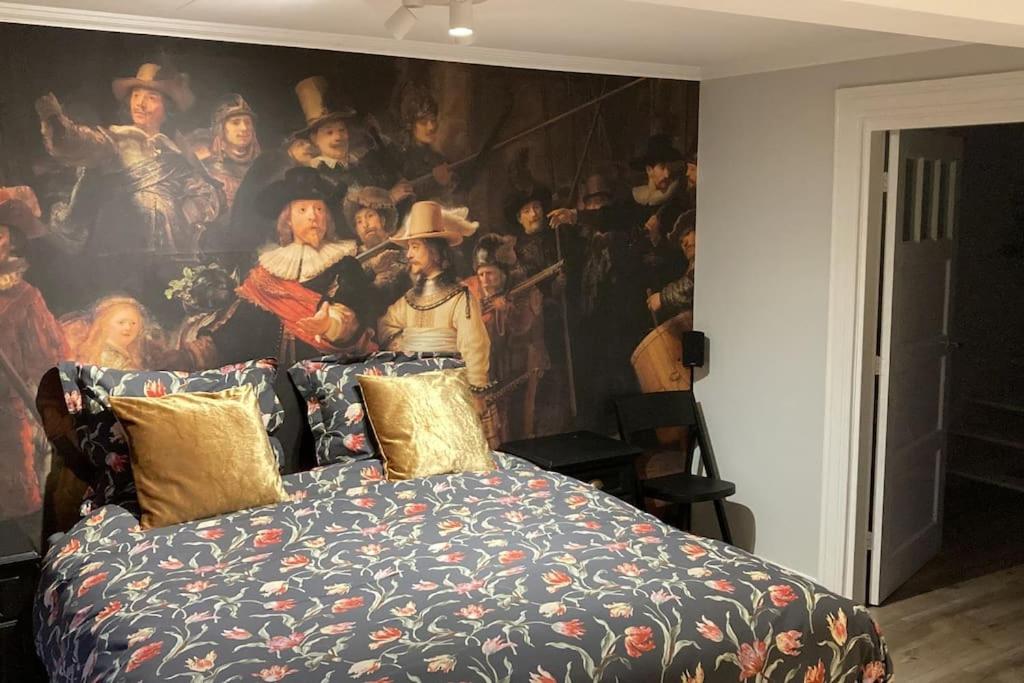 een slaapkamer met een groot schilderij aan de muur bij Voorsterstaete former barn, including jacuzzi in Voorst