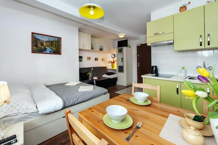 a room with a bed and a table and a kitchen at Cosy Studio Apartment in Krakow