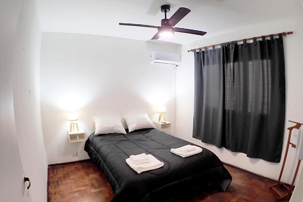 1 dormitorio con cama negra y ventilador de techo en Departamento Bouquet en 