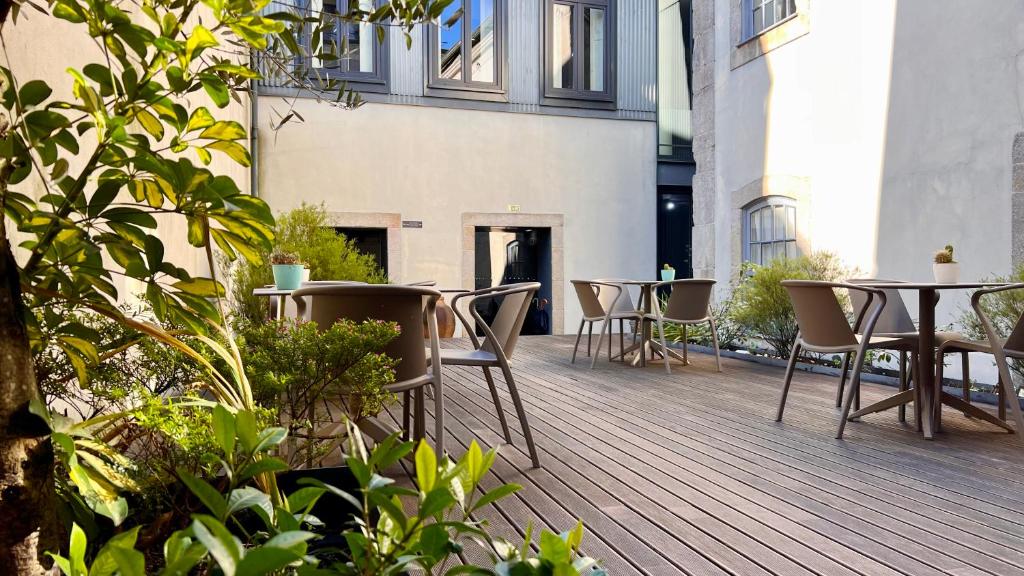 una terraza de madera con mesas y sillas en un edificio en Casa dos Lóios by Shiadu, en Oporto