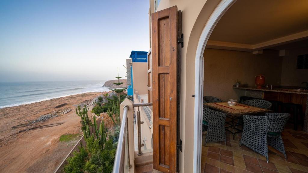 a door leading to a balcony with a table and the ocean at Dar diafa samira in Mirleft