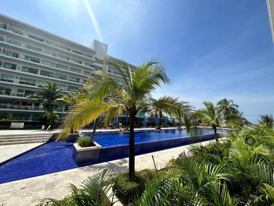 a swimming pool with palm trees in front of a building at The Cartagena Charming Beachfront Hideaway in Cartagena de Indias