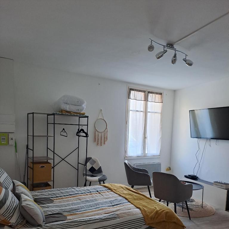 - une chambre avec un lit, des chaises et une télévision dans l'établissement Studio de charme, à Saint-Maixent-lʼÉcole