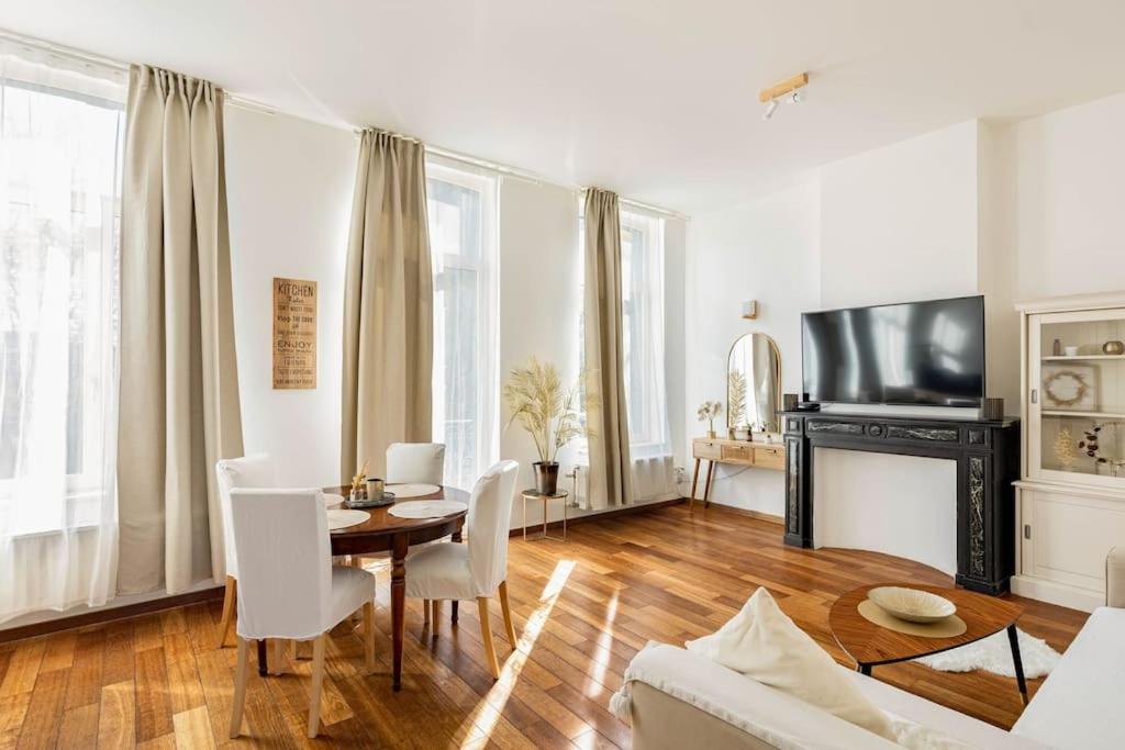 een woonkamer met een tafel en stoelen en een televisie bij Luxueux appart proche de gare du Midi, à côté du Centre Ville in Brussel