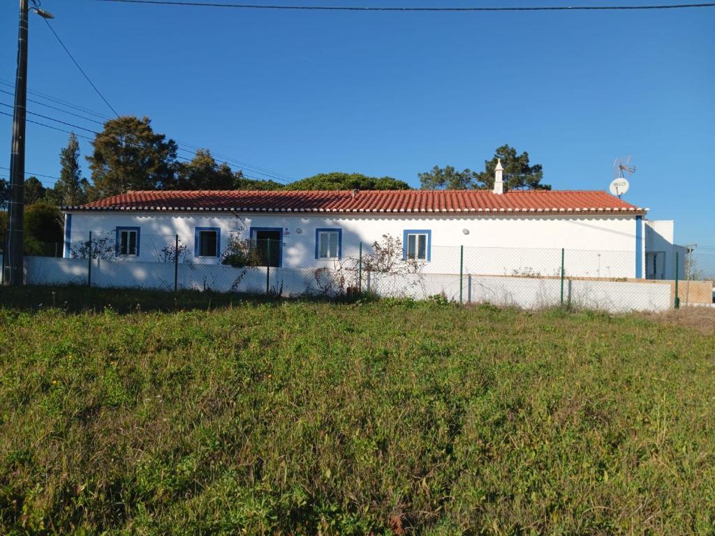 Biały dom z płotem przed polem w obiekcie Quinta do Pinhal Novo w mieście Chabouco