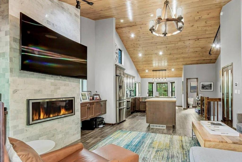 a living room with a fireplace and a tv on a wall at Luxury Modern Townhome steps to ski lifts and downtown with Nature at your patio in Breckenridge