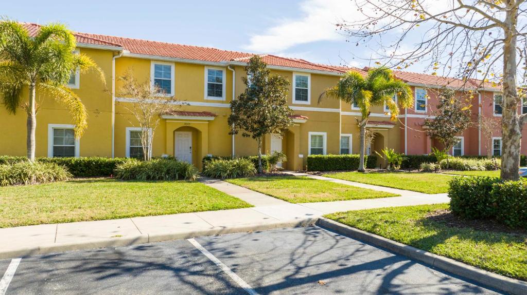 een geel huis met palmbomen en een oprit bij 3065 Beautiful comfortable home for your vacation in Kissimmee