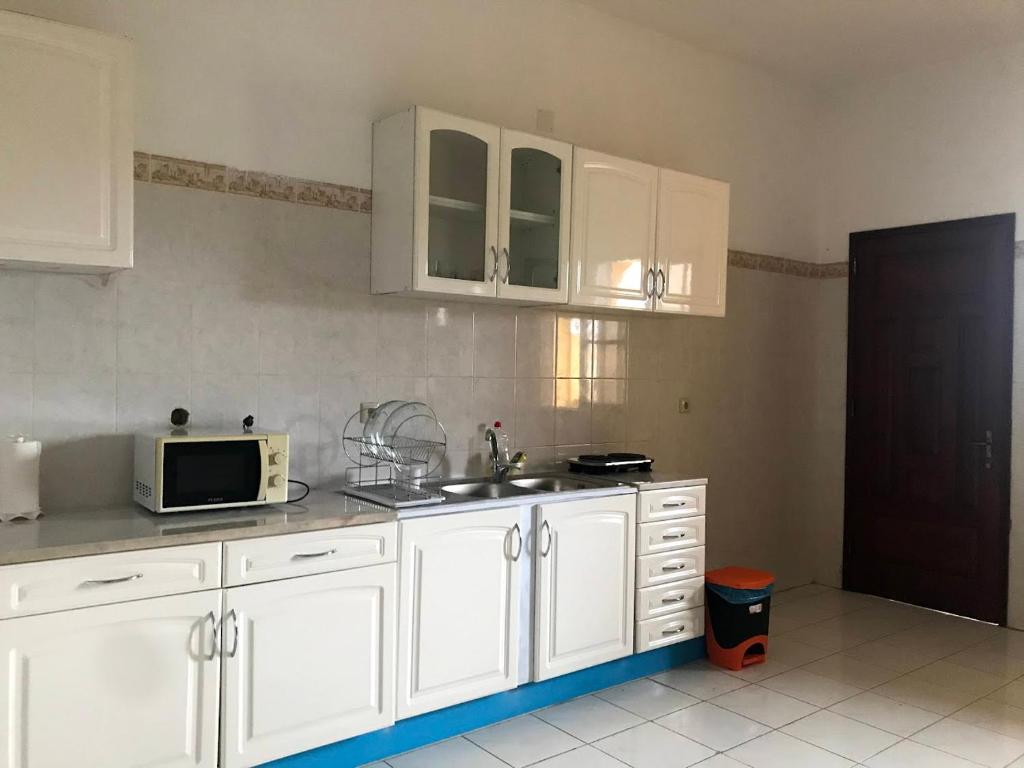 a kitchen with white cabinets and a sink and a microwave at Holiday Homes in Nazaré