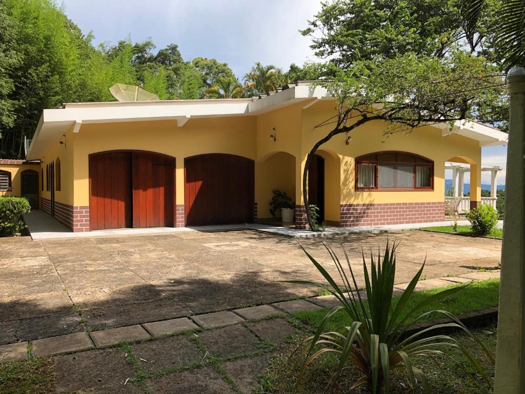 a yellow house with a driveway at Recanto Arlecchino in Águas de Lindóia