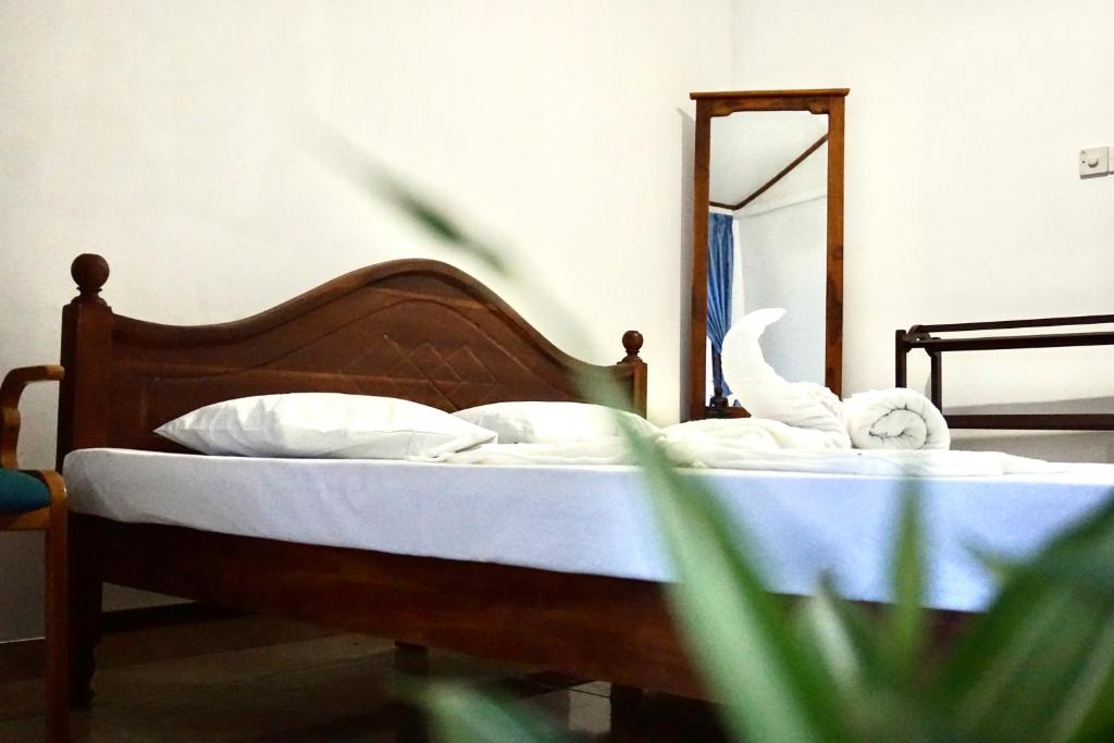 una camera da letto con un letto con lenzuola bianche e uno specchio di Talalla Village Beach Resort a Talalla South