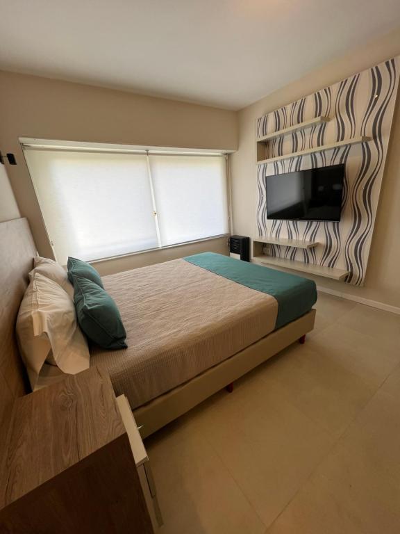 a bedroom with a bed and a flat screen tv at Departamento Rivadavia in Mar del Plata