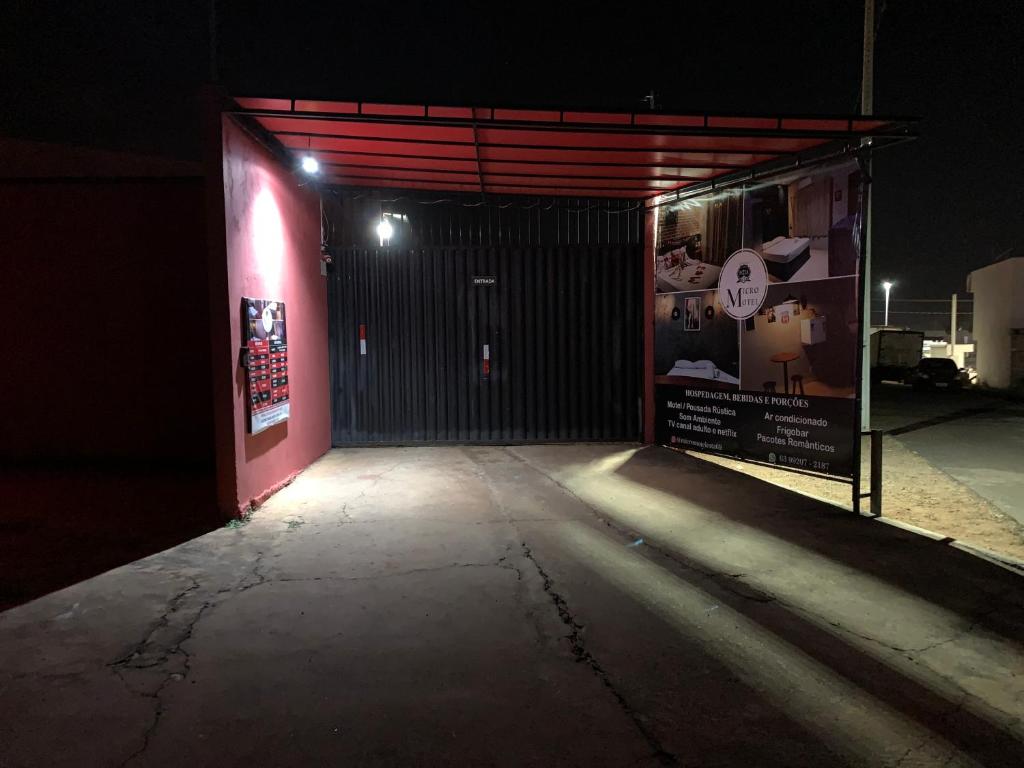 Rota 69 Motel & Pousada في Porto Nacional: كراج في الليل مع باب احمر