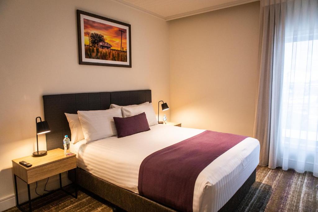 a hotel room with a bed and a window at Porter's Plainland Hotel in Plainland