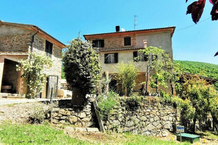una casa vieja con una pared de piedra delante de ella en Casa Lepri, en Poggioni