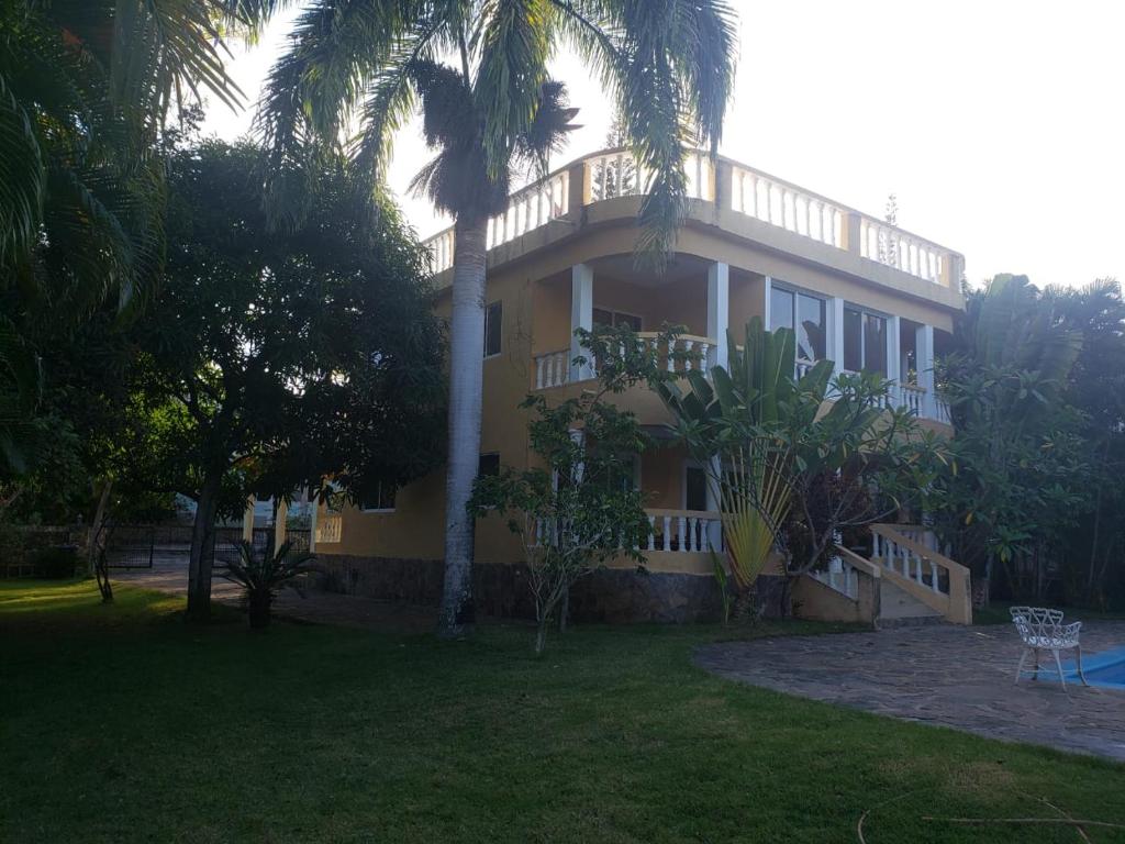 una gran casa amarilla con palmeras en el patio en 4 bedroom villa, security, private pool, ocean view, en Sosúa